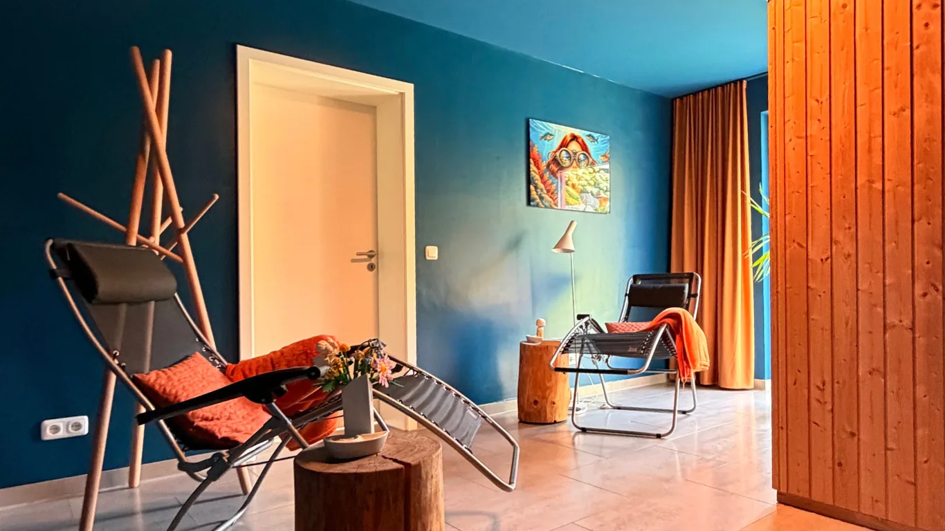 Ruheraum mit zwei Liegen vor blauer Wand, rechts die Saunakabine